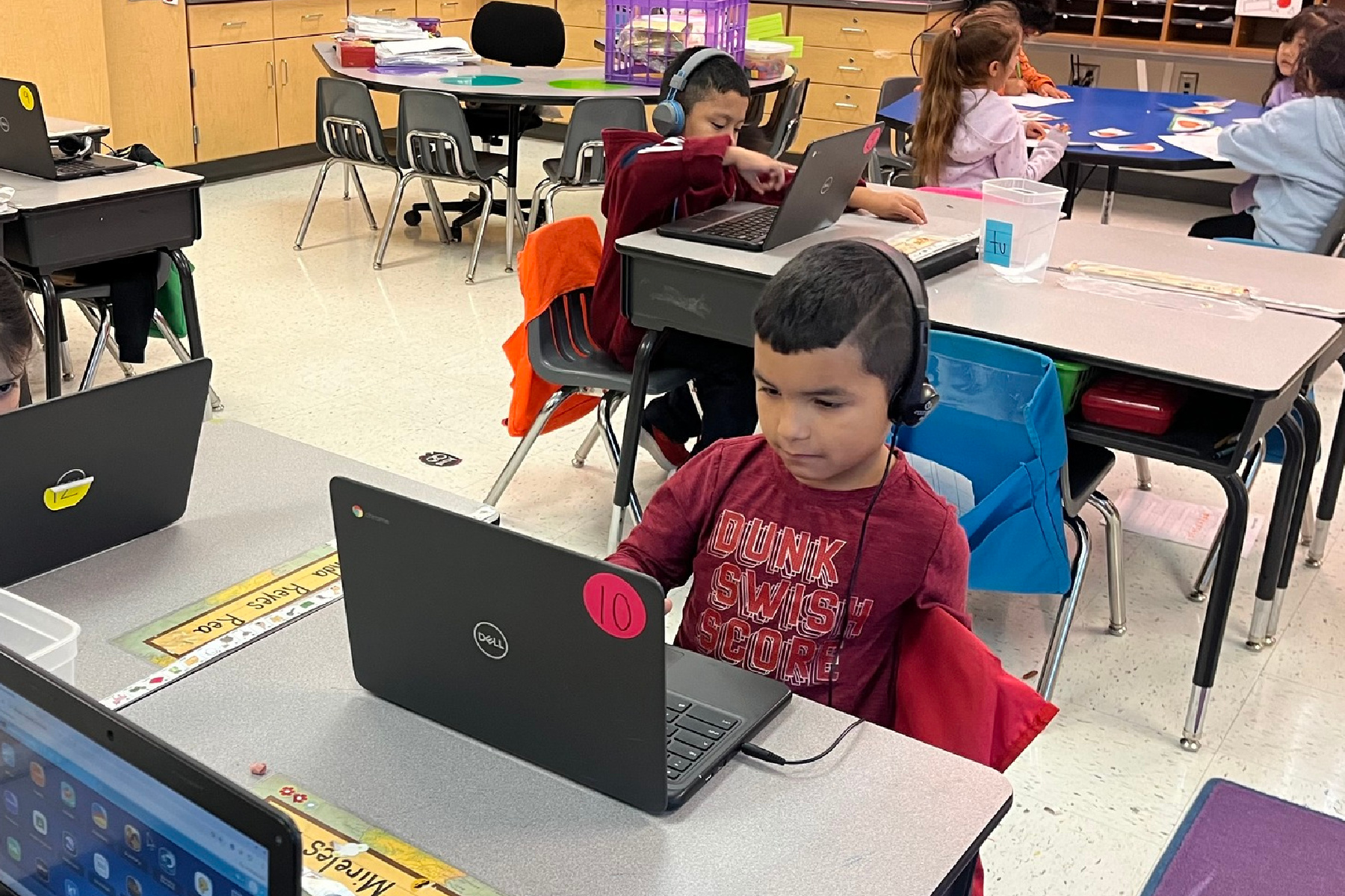 A young student is using a laptop in a classroom.